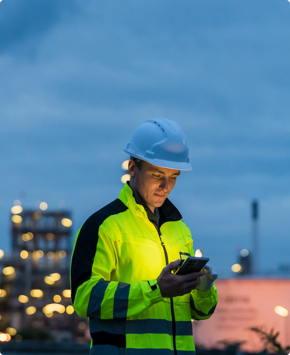 Worker in helmet using phone outdoors