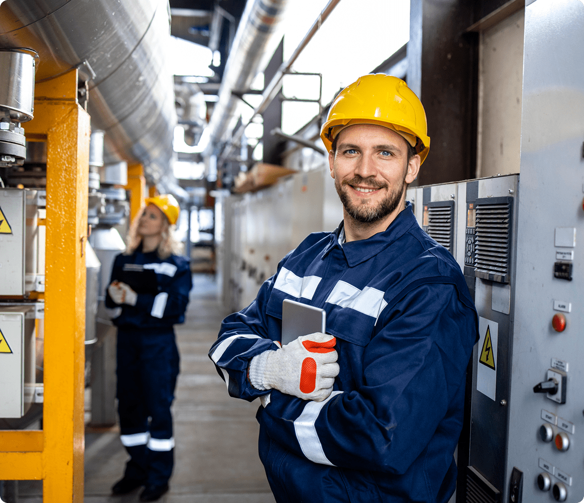 Worker in factory wearing safety gear smiling.